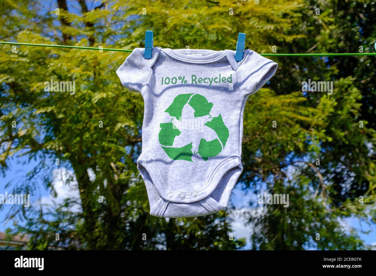 Recycling Kleidung Symbol auf Babygro Trocknen außen auf Wäscheleine mit 100% recyceltem Text, nachhaltige Mode Konzept Illustration Wiederverwendung, Recycling Kleidung Stockfoto