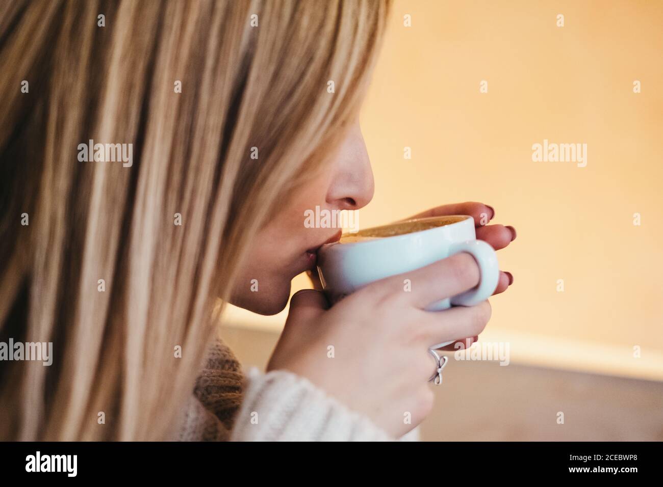 Seitenansicht Ernte attraktive Dame in Pullover hält Tasse von†hot Trinken Sie in der Nähe von Lippen Stockfoto