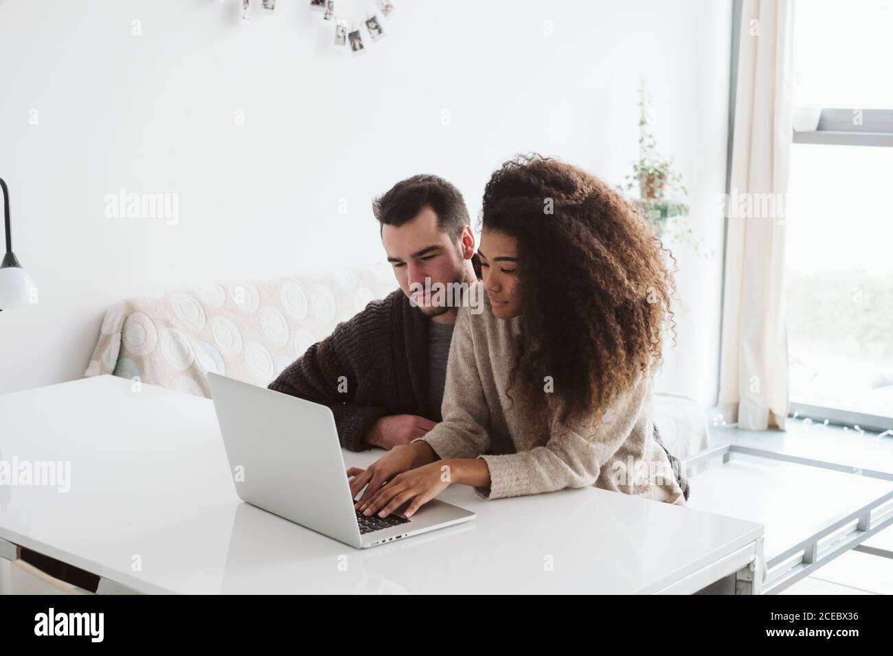 Fröhliche multiethnische Paar mit Laptop zusammen Stockfoto