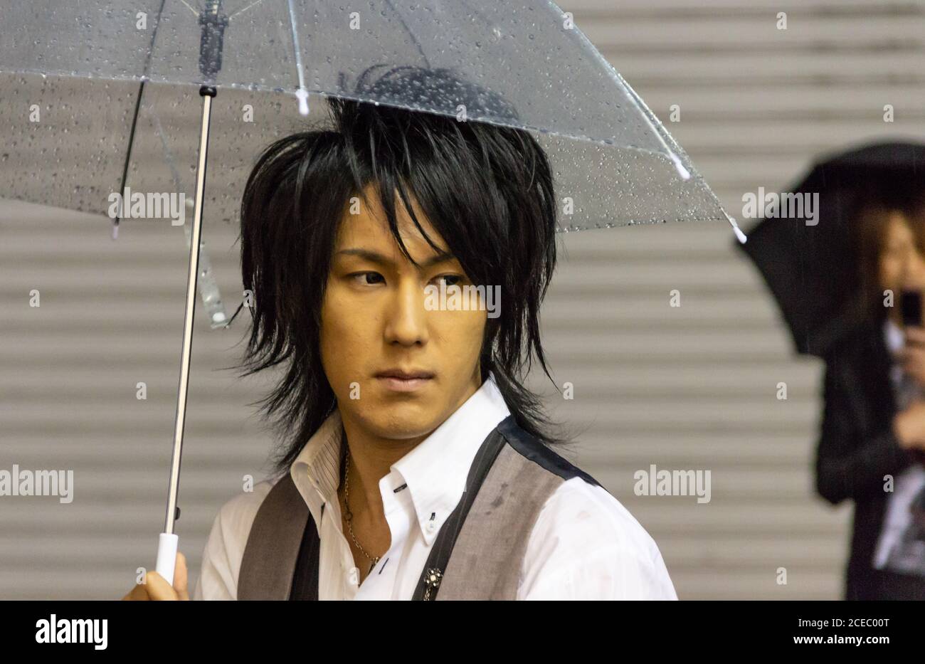 Japan - Mai, 10 2013: Stilvoller Asiatisch mit transparentem Schirm, der an regnerischen Tagen auf der Stadtstraße steht und wegschaut Stockfoto