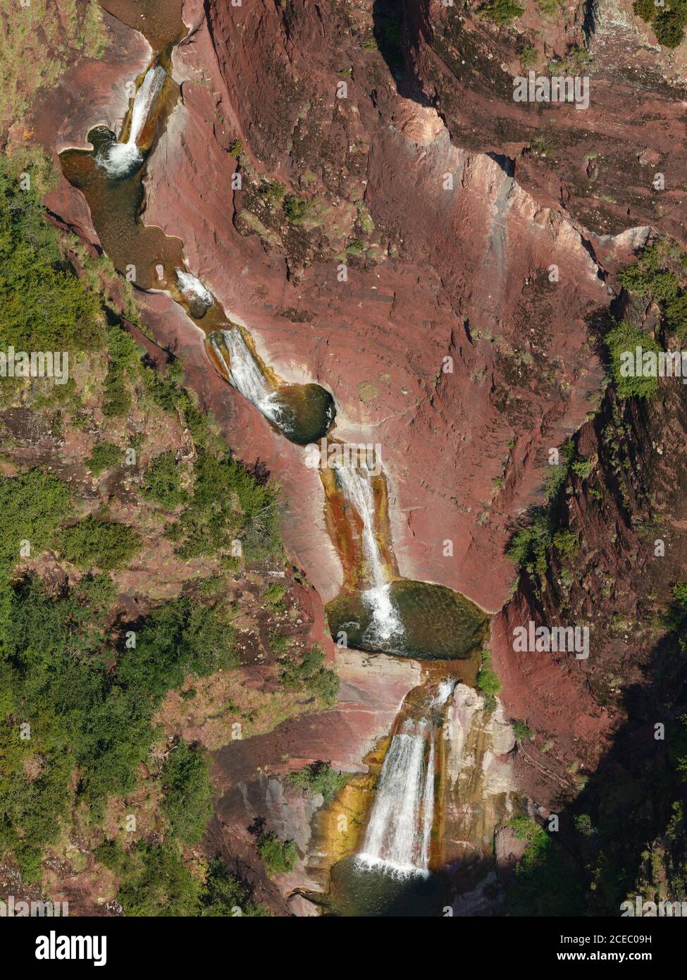 LUFTAUFNAHME. Mehrstufiger Wasserfall mit Tauchbecken in einer Landschaft aus roten Peliten. Vallon de Challandre, Beuil, Alpes-Maritimes, Frankreich. Stockfoto