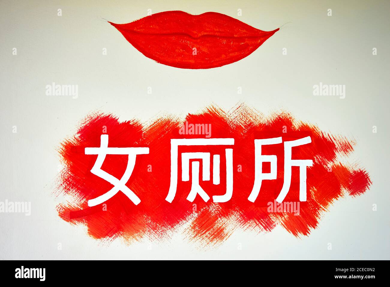 Wandkunst mit chinesischen Wörtern und roten Lippen, die auf die Toilette hinweisen Für Frauen Stockfoto