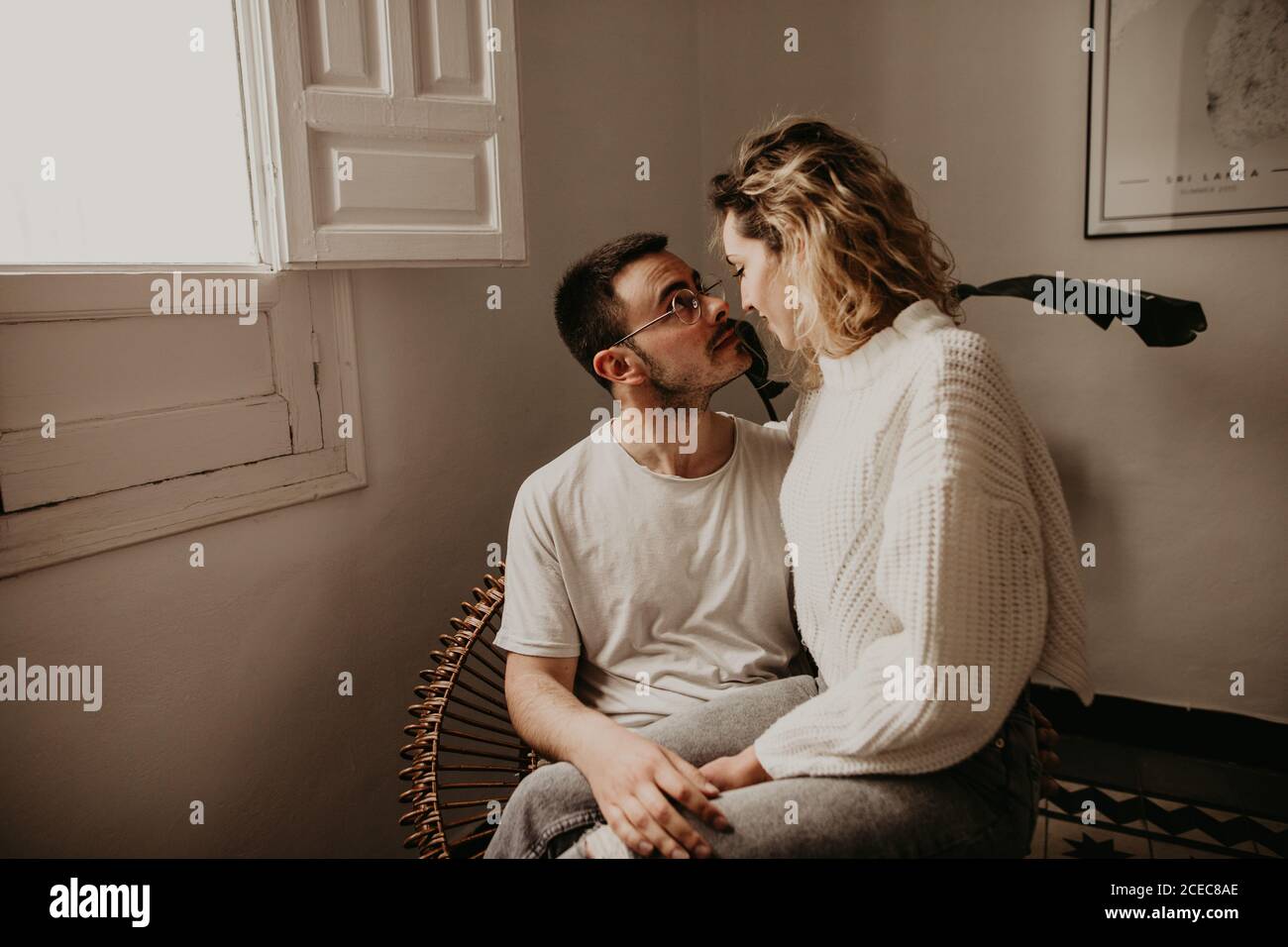 Glückliches erwachsenes Paar, das im Sessel sitzt und sich ansieht, während man zu Hause klebt. Stockfoto