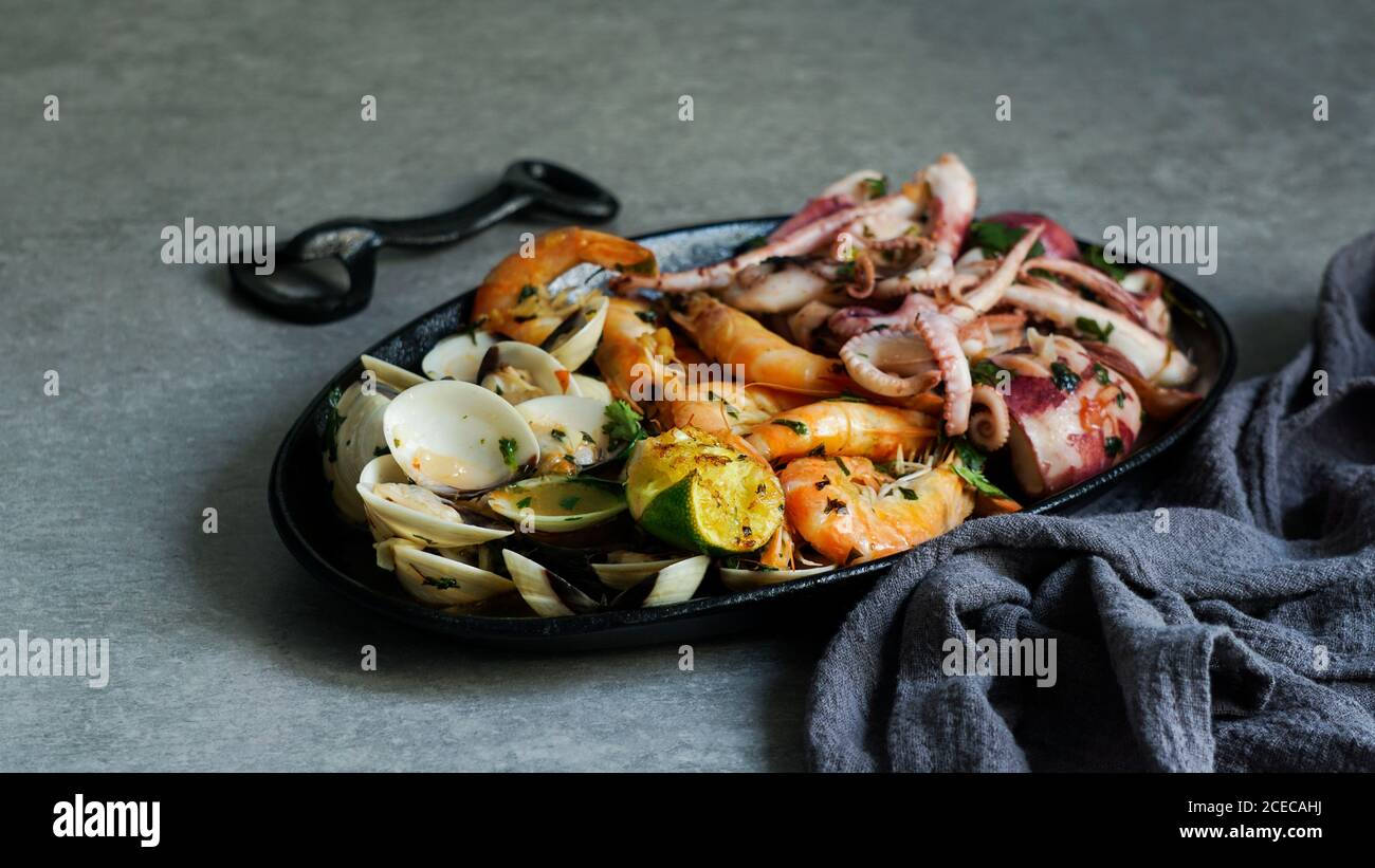 Von oben lecker gegrillten Oktopus, Austern und Garnelen mit Kalk und Kräutern auf Gusseisen Platte in der Nähe von Serviette Stockfoto