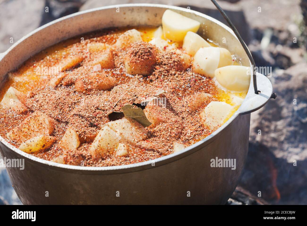 Würzige Suppe mit Gemüse, das in einem Kessel kocht. Offenes Feuer Kochen, Camping Essen Stockfoto