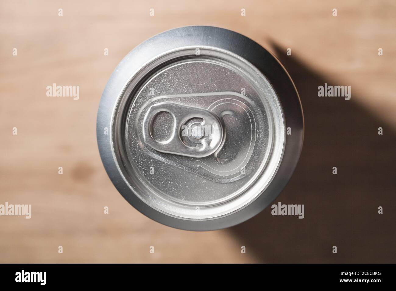 Geschlossene glänzende Aluminium-Dose steht auf einem Holztisch, Standard-Softdrink-Verpackung. Draufsicht Stockfoto