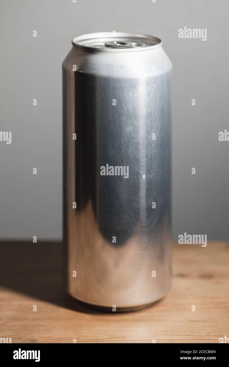 Geschlossene glänzende Aluminium-Dose steht auf einem Holztisch, Standard-Softdrink-Verpackung Stockfoto