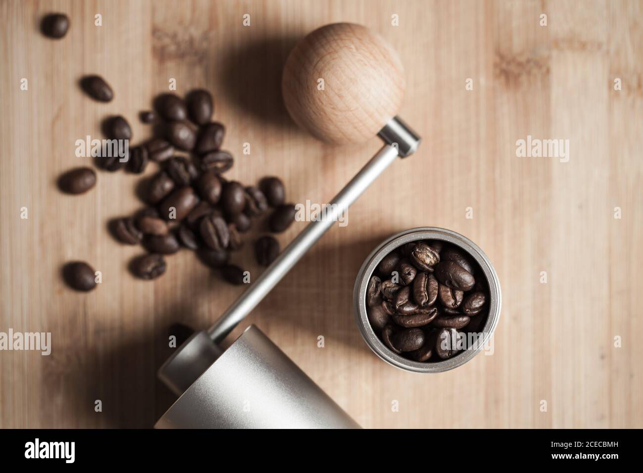 Manuelle Kaffeemühle und geröstete Kaffeebohnen sind auf Holztisch, flach Lay Foto mit weichem Fokus Stockfoto