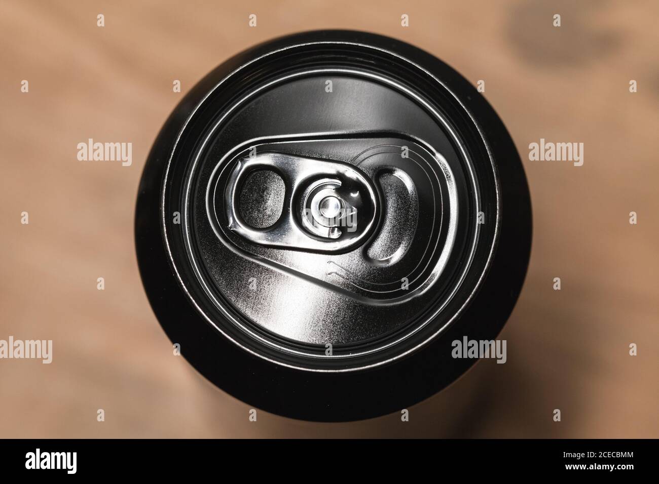Geschlossene glänzende schwarze Aluminium-Dose steht auf einem Holztisch, Standard-Softdrink-Verpackung. Draufsicht Stockfoto