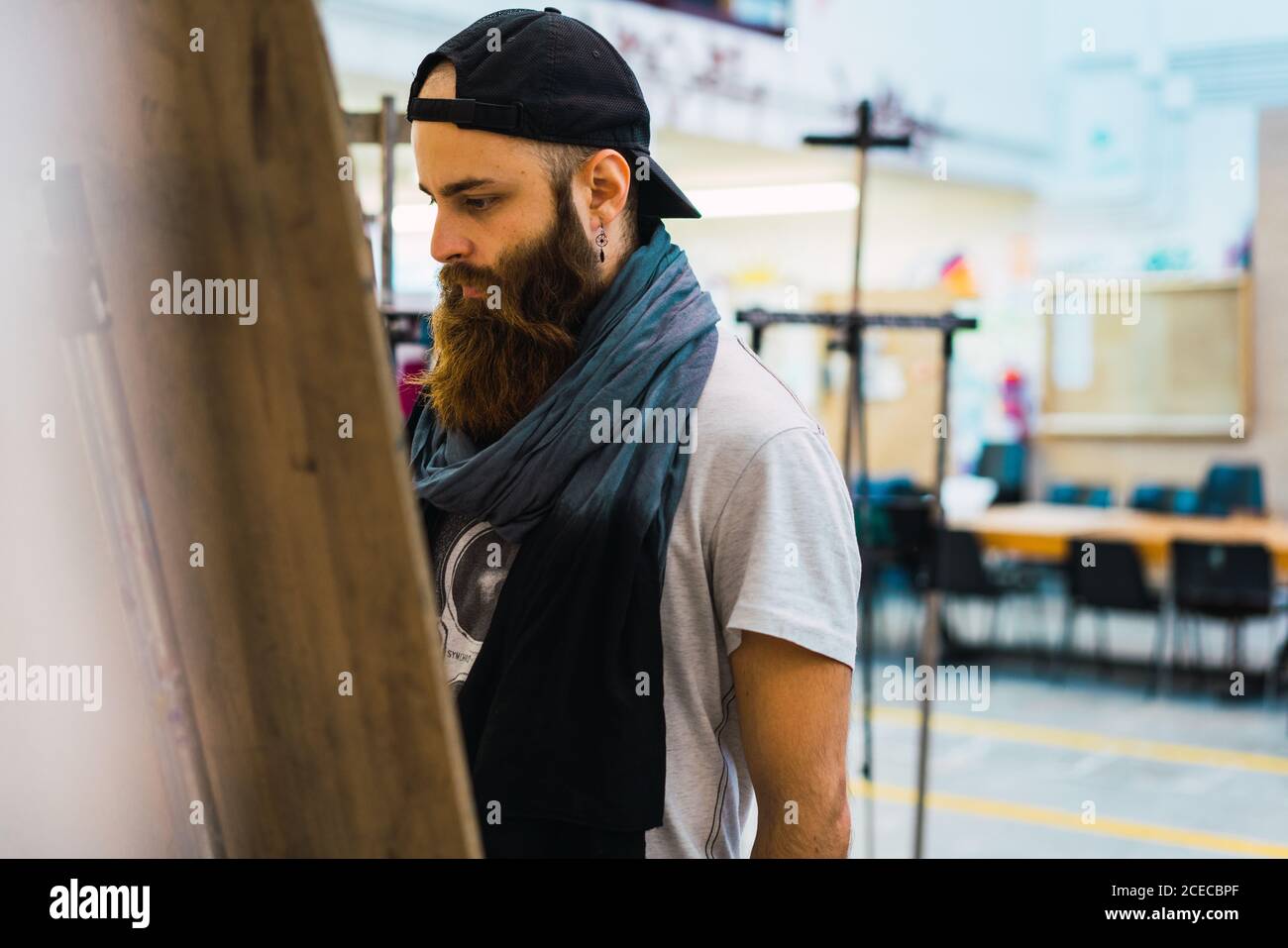 Bärtiger Mann, der auf Staffelei zeichnet Stockfoto
