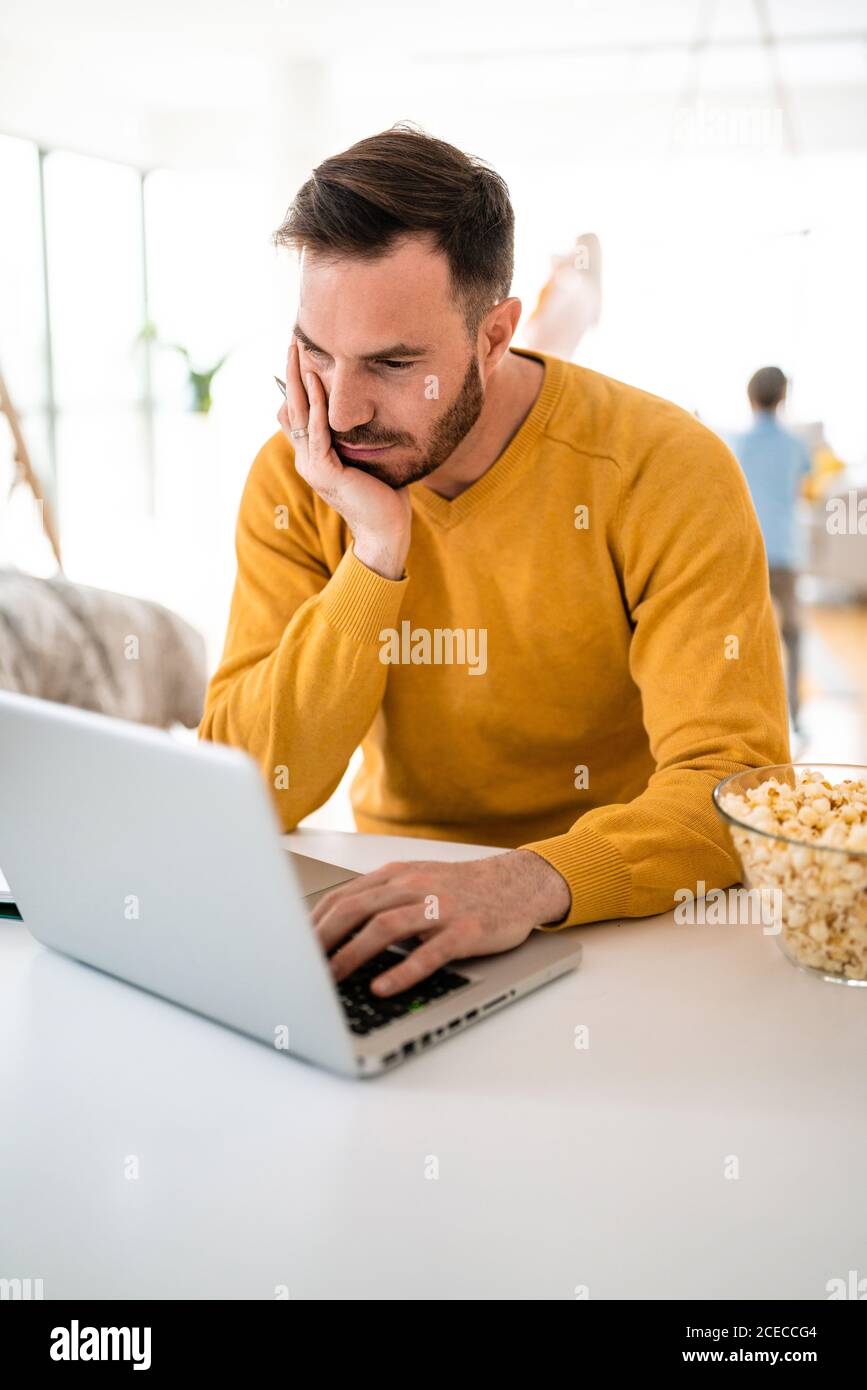 Frustrierter junger Mann, der zu Hause am Laptop arbeitet Stockfoto