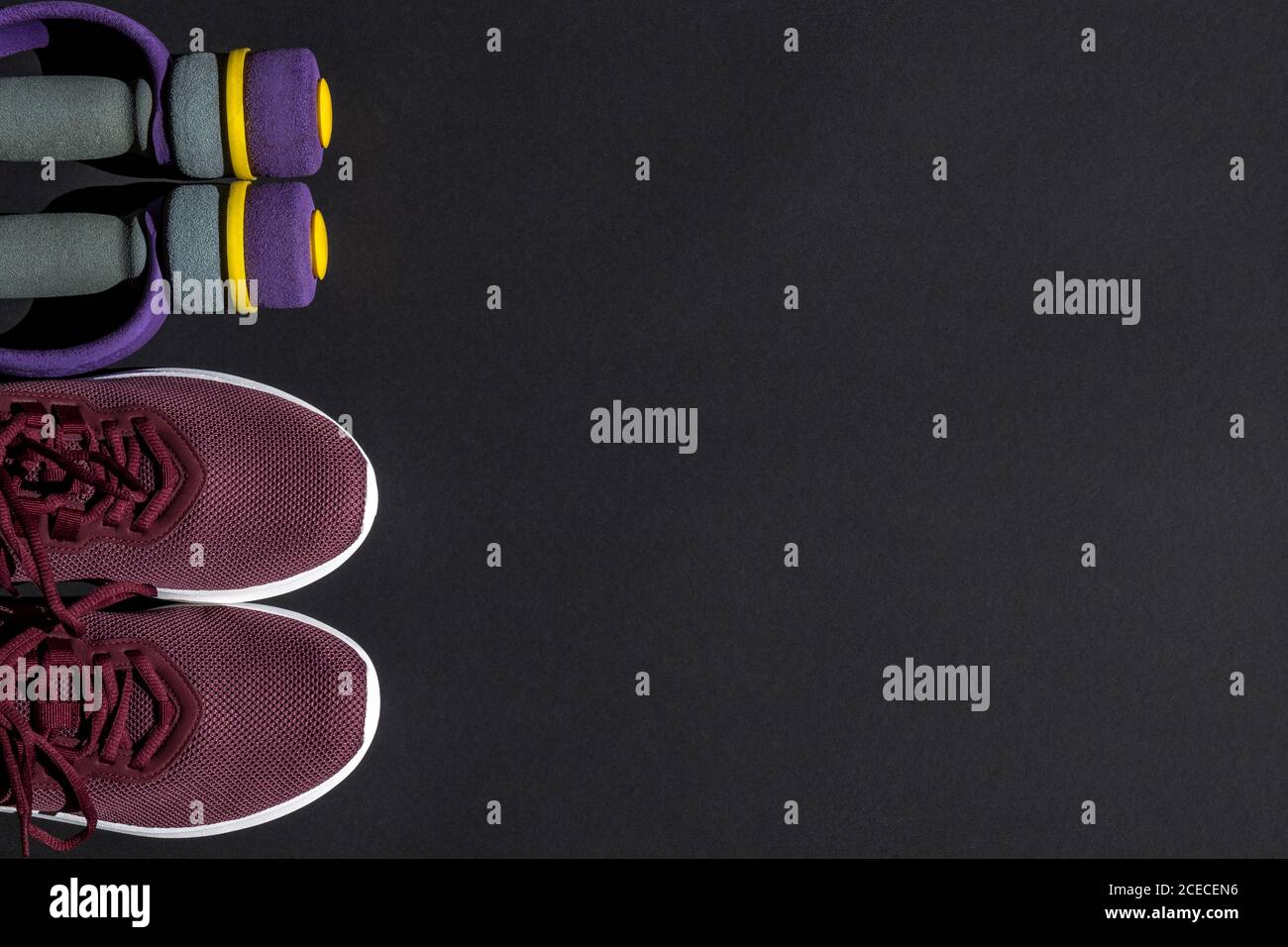 Sneaker und Hanteln für das Training zu Hause und im Fitnessstudio auf dunklem Hintergrund. Körperpflegekonzept, aktiver Lebensstil. Draufsicht. Leerzeichen für Text. Stockfoto
