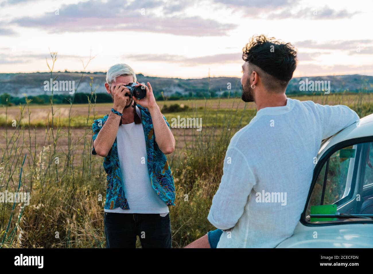 Casual Mann im Hemd mit Fotokamera und Bild Mann Mit dem Auto in Landschaft im Sommer Stockfoto