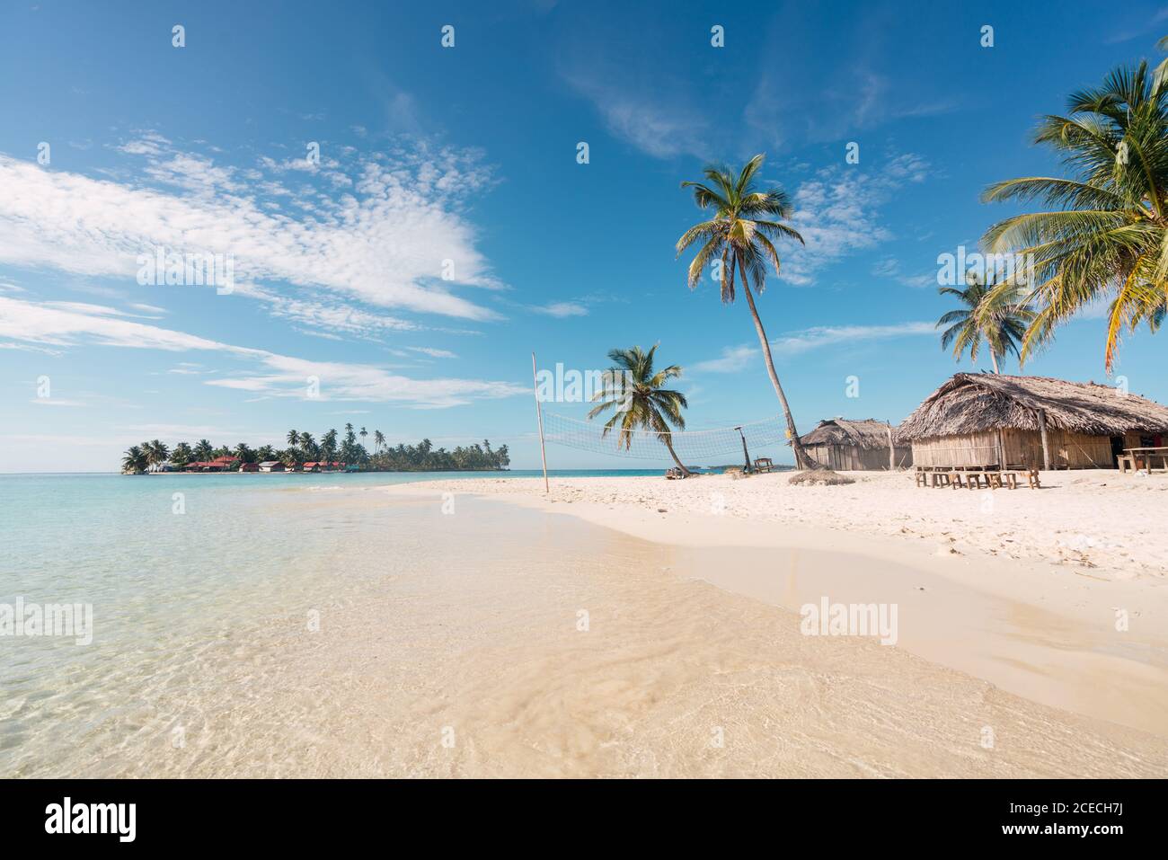 Sandstrand mit Palmen und Gebäude in der Nähe der Wasseroberfläche Stockfoto