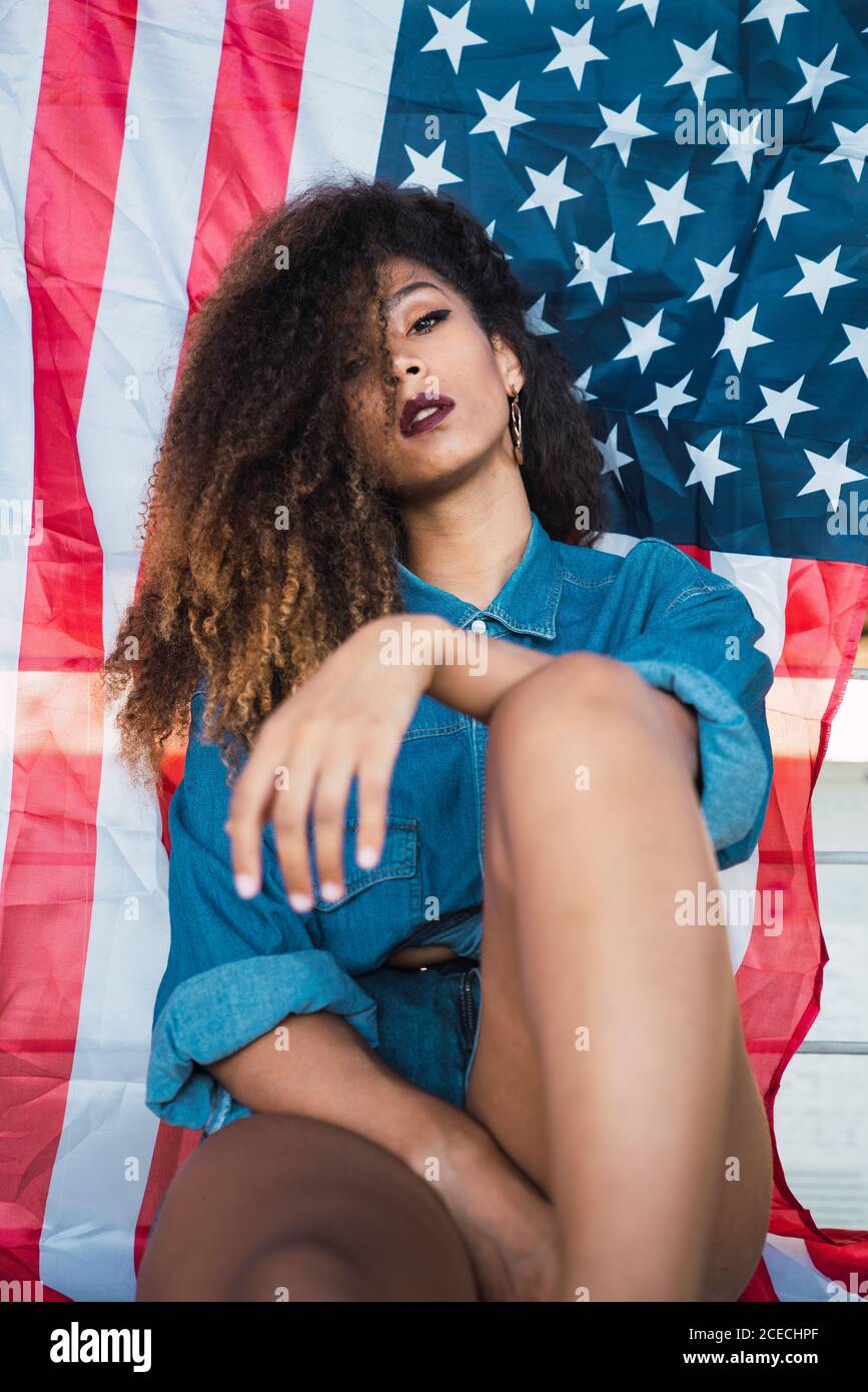 Junge Frau, die in der Nähe der Flagge Amerikas sitzt Stockfoto