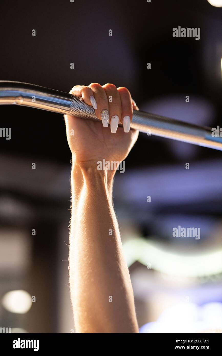 Crop-Ansicht der Hand einer Frau, die im Fitnessstudio Lat Pull Down trainiert, auf verschwommenem Hintergrund Stockfoto
