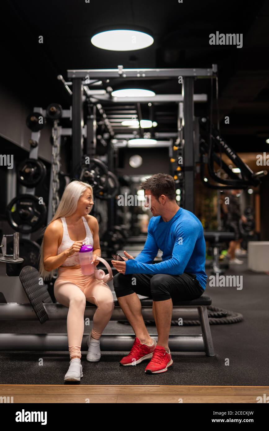 Mann und Frau sitzen im Fitnessstudio und lachen Stockfoto