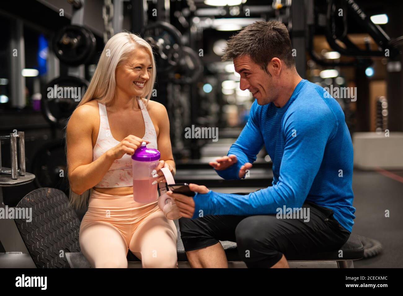 Mann und Frau sitzen im Fitnessstudio und lachen Stockfoto
