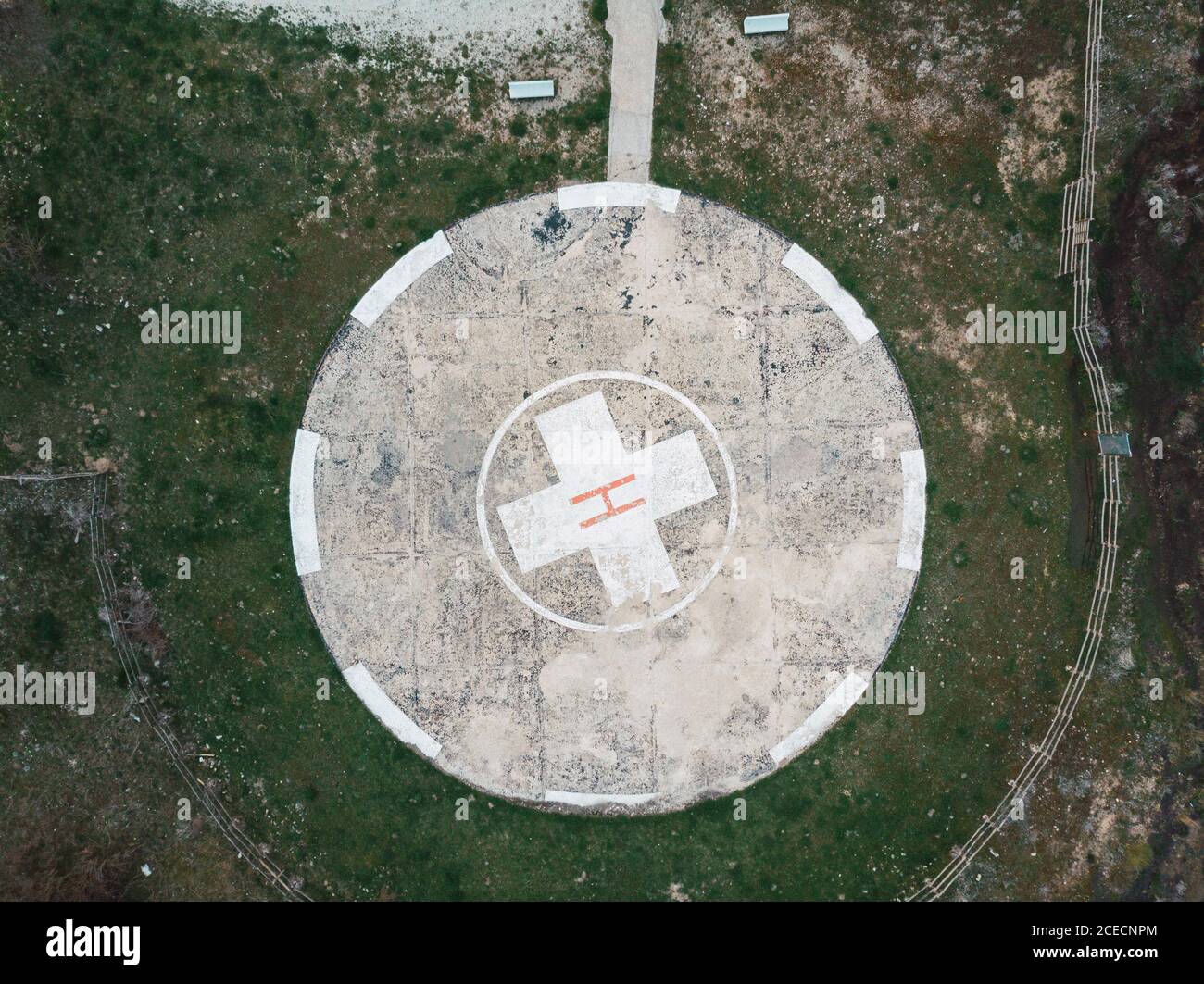 Schäbiger Abheben Platz mit rotem H Buchstabe und grauer Runde Platz auf grünem Gras Stockfoto