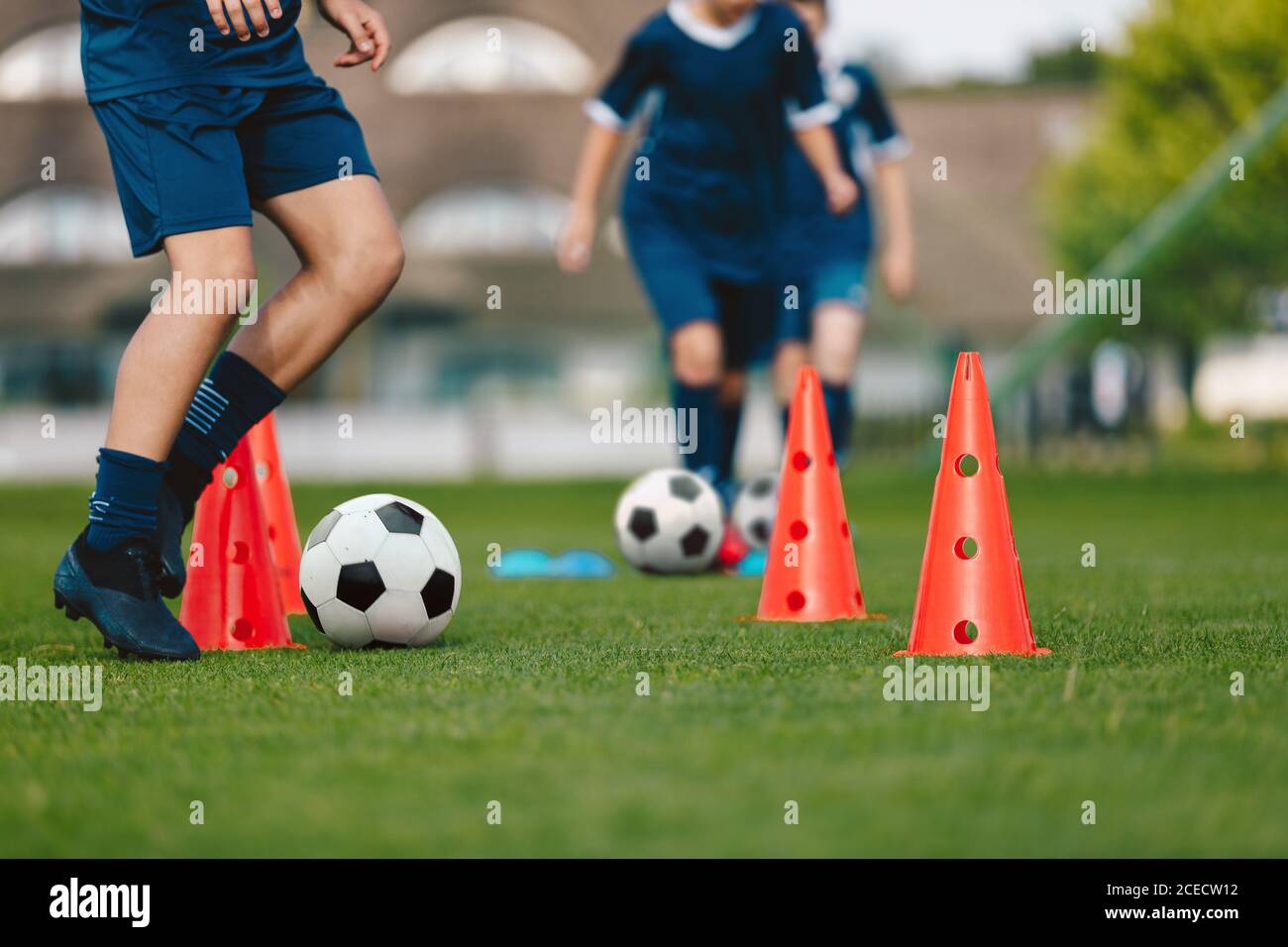 Training mit Kegeln. Fußballtraining für Kinder auf Fußball-Camp. Junge in der Kinder-Fußballmannschaft auf Training. Kinder üben im Freien mit einem Stockfoto