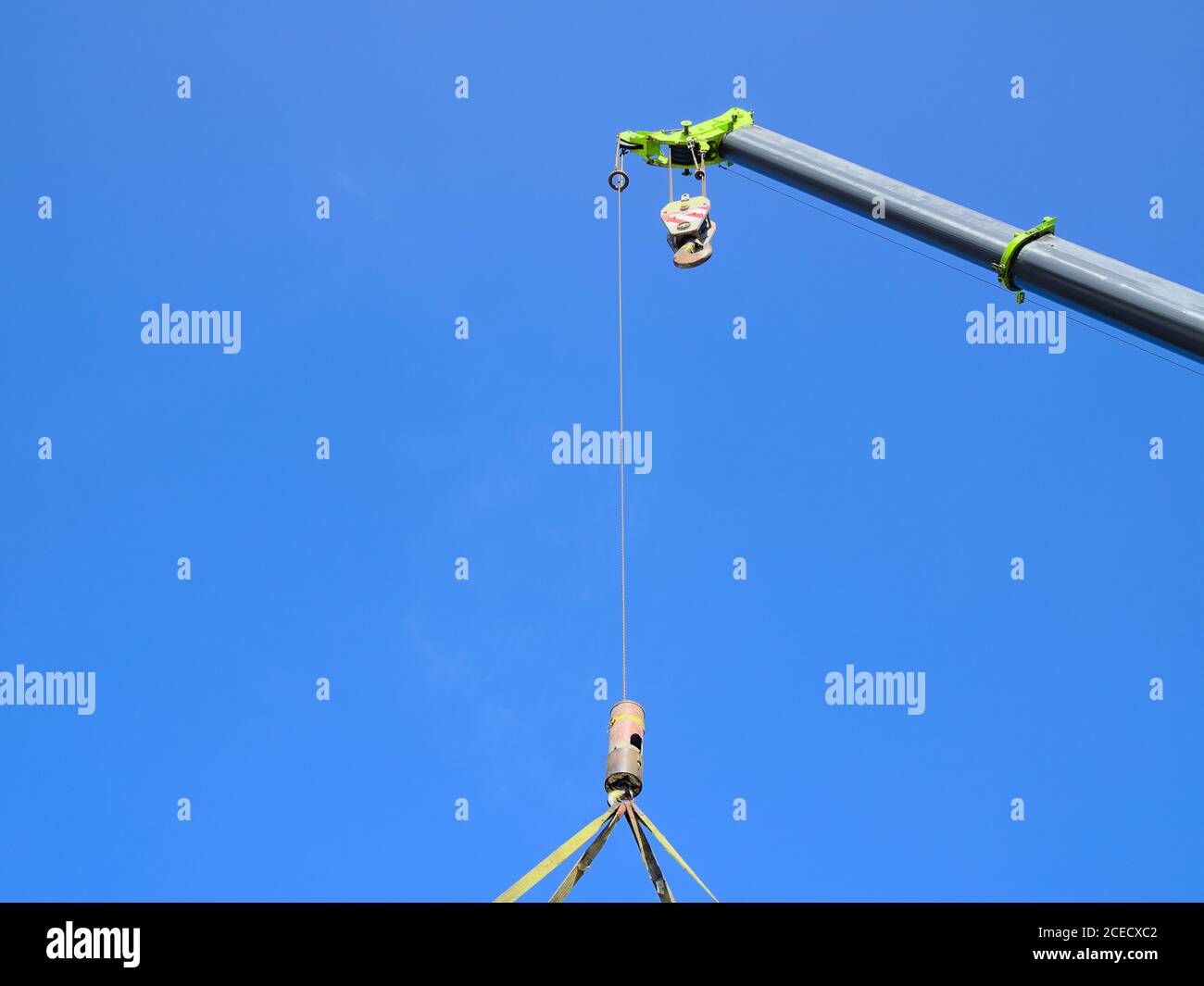 Schwerer Kran voll ausgefahren, während der Hebezeug und die Kette in der Luft schwingen. Stockfoto
