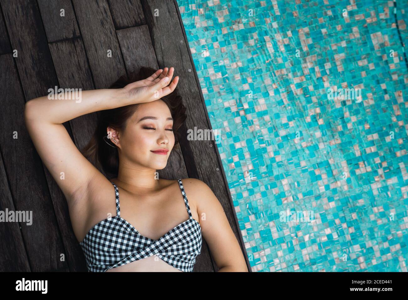 Lächelnde Frau, die sich am Pool entspannt Stockfoto