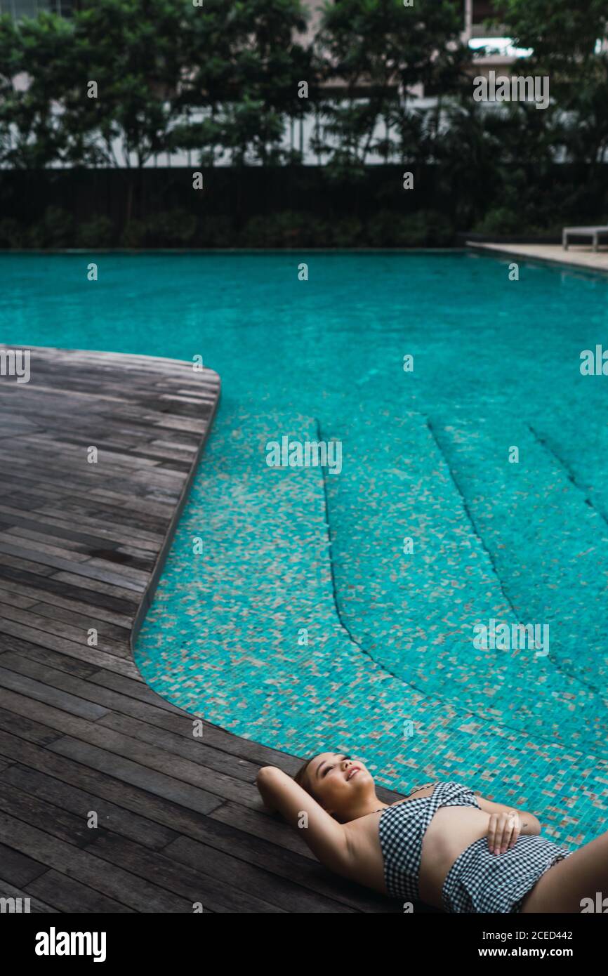 Lächelnde Frau, die sich am Pool entspannt Stockfoto