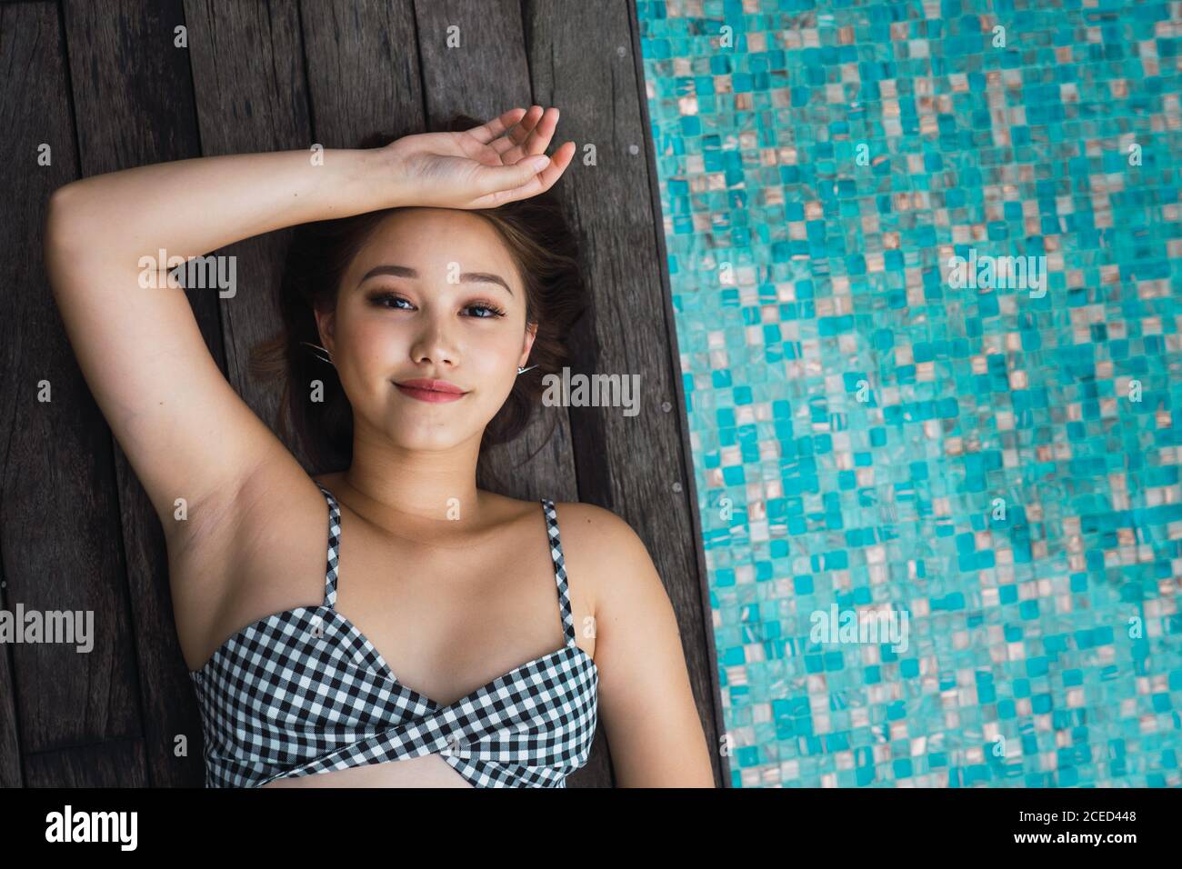 Lächelnde Frau, die sich am Pool entspannt Stockfoto