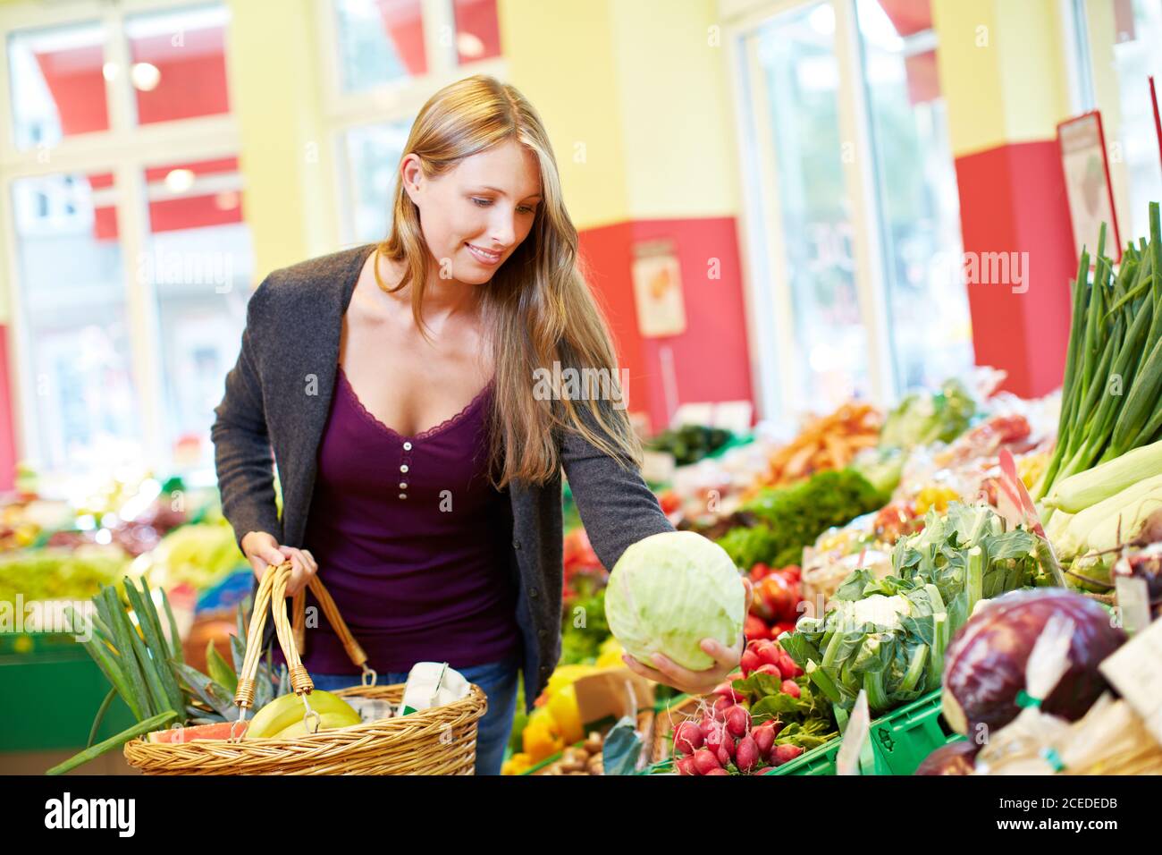 Junge lächelnde Frau kauft Kohl und anderes Gemüse in der Gesundheit Lebensmittelgeschäft Stockfoto