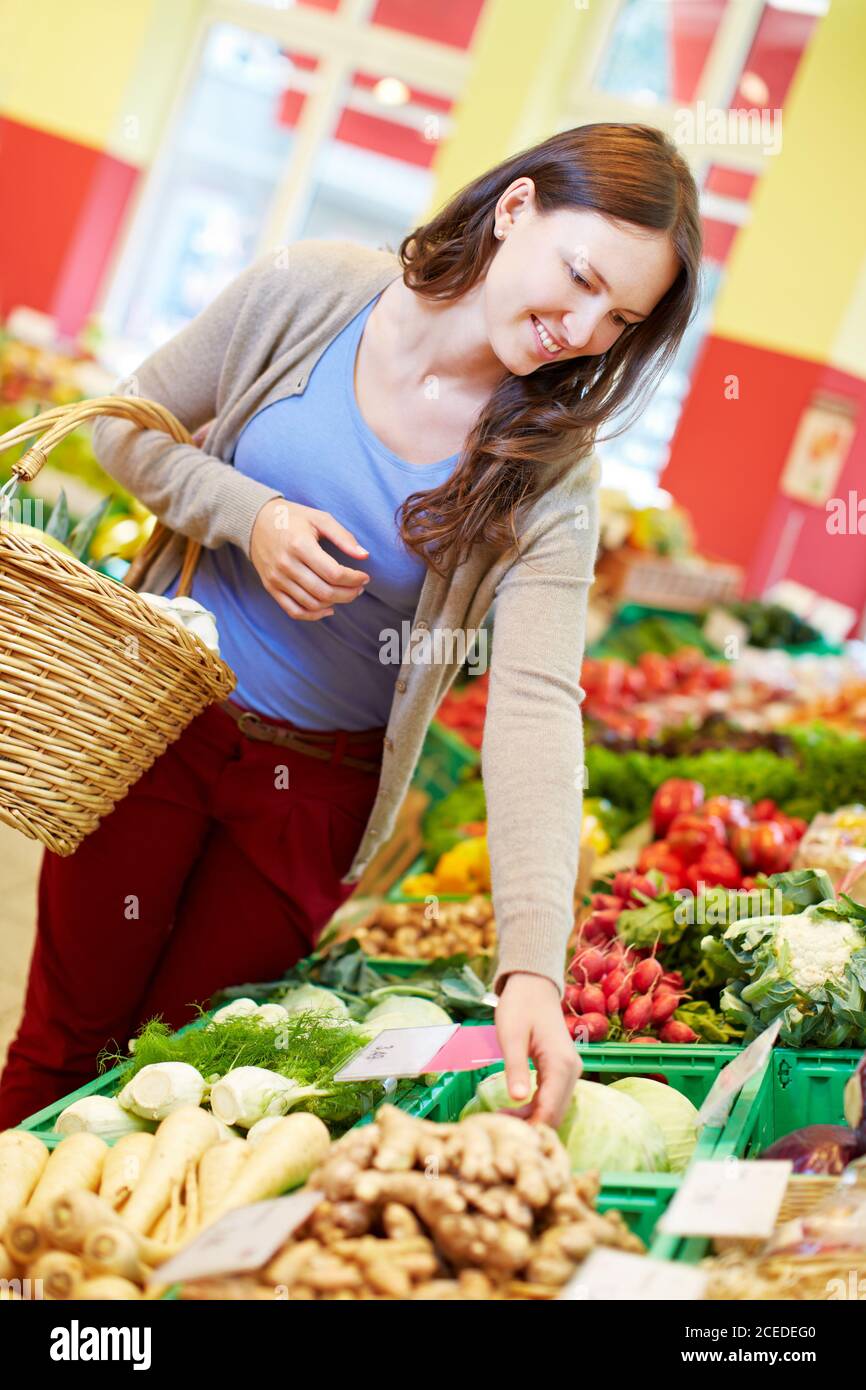 Junge Frau mit Einkaufskorb kauft frisches Gemüse in der Gesundheit Lebensmittelgeschäft Stockfoto