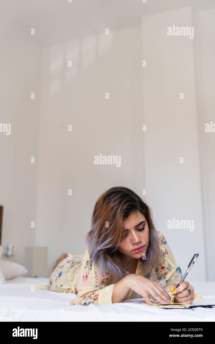 Schöne links - weibliche Notizen in kleinen Notebook übergeben, während auf  einem weichen Bett in einem der gemütlichen Zimmer liegen Stockfotografie -  Alamy