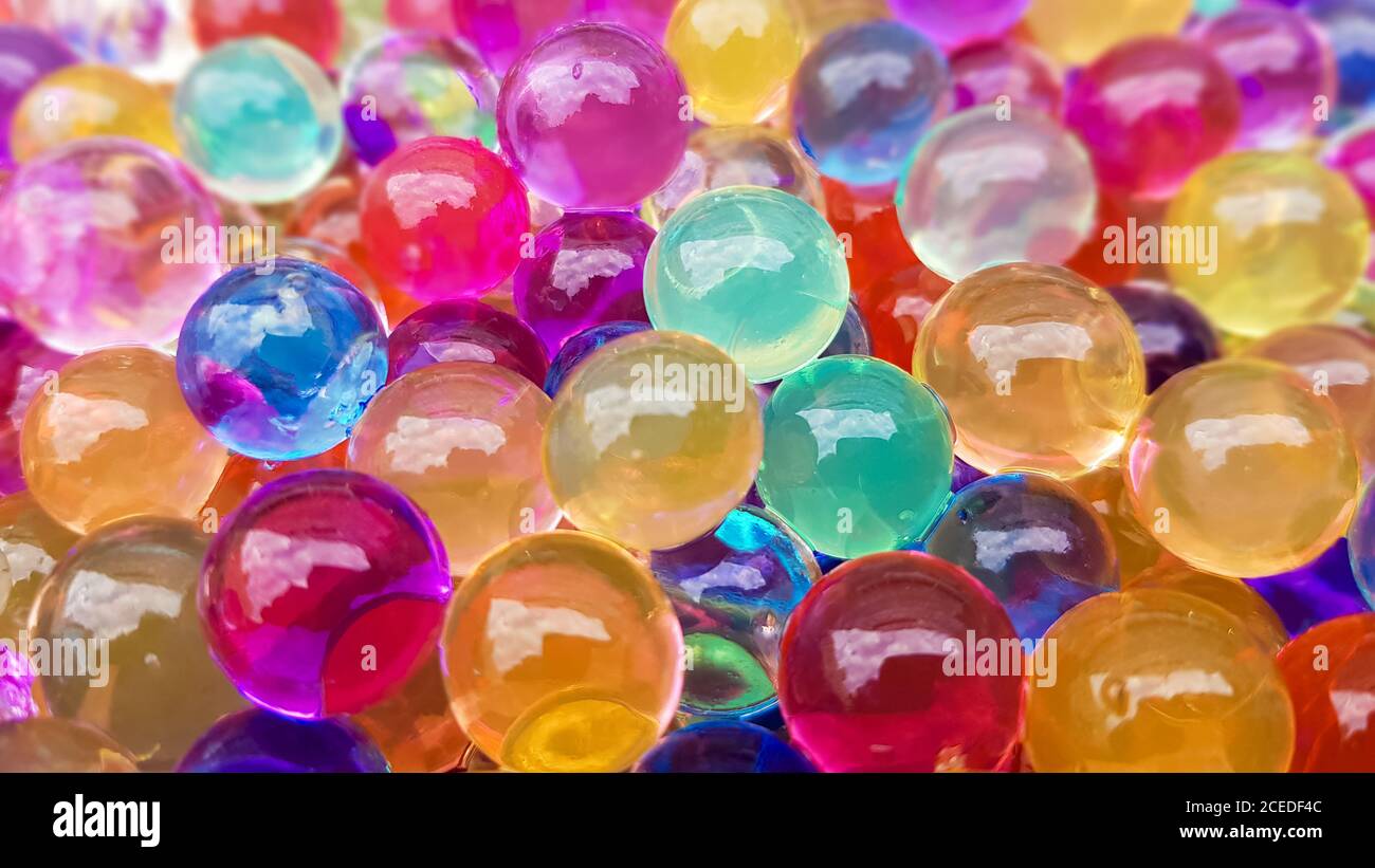 Viele verschiedene farbige Hydrogelkugeln. Set von mehrfarbigen orbis. Kristallwasserperlen für Spiele. Heliumballons. Kann als Hintergrund verwendet werden. Poly Stockfoto