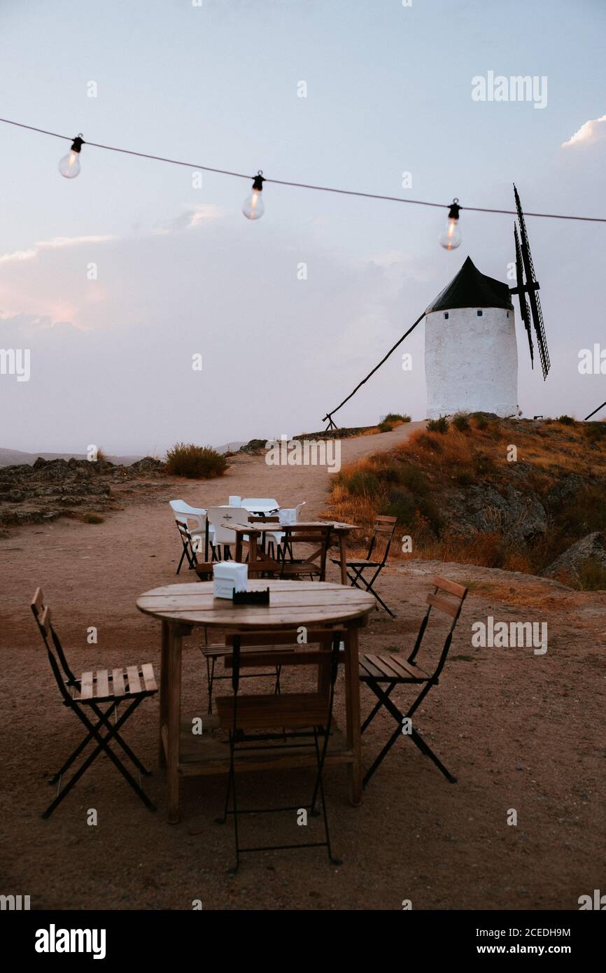 Kleine runde Tische und bequeme Stühle stehen auf dem Weg in der Nähe der alten Windmühle in der Landschaft in der Nähe von Toledo, Spanien Stockfoto