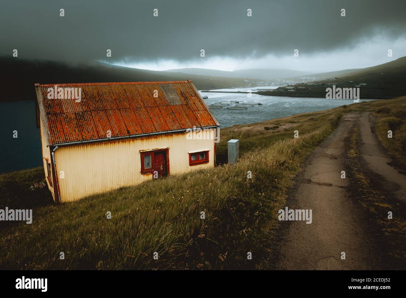 Kleines grungiges Haus mit rostigen Dach am Seeufer gebaut Auf Feroe Island in bewölktem Tag Stockfoto Kleines grungiges Haus mit rostigen Dach am Seeufer gebaut Auf Feroe Island in bewölktem Tag Stockfoto