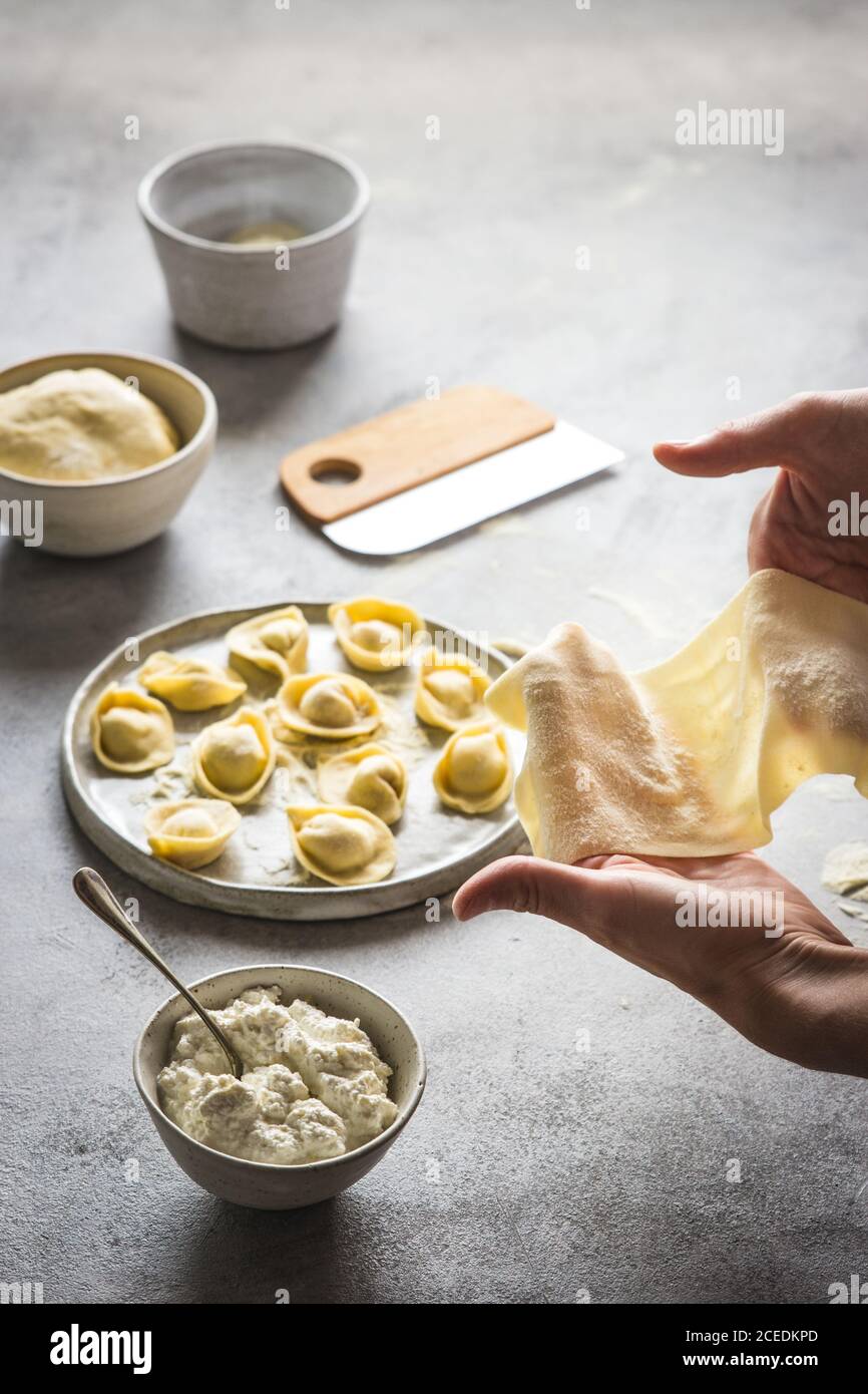 Crop Person Herstellung Tortellini mit Hüttenkäse Stockfoto