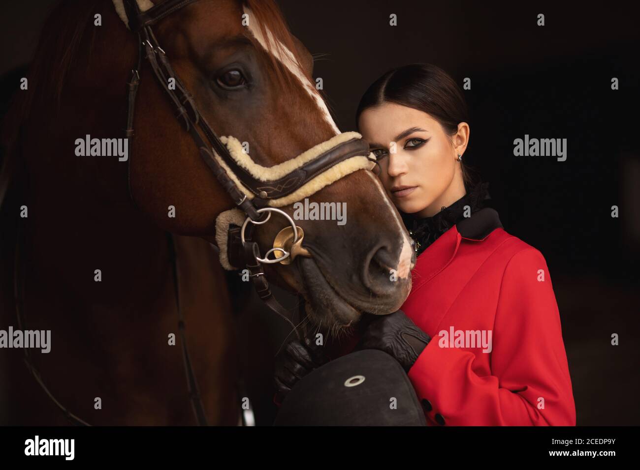 Frau Jockey Reiter umarmt braunes Pferd mit geschlossenen Augen. Konzept Liebe Tiere Stockfoto
