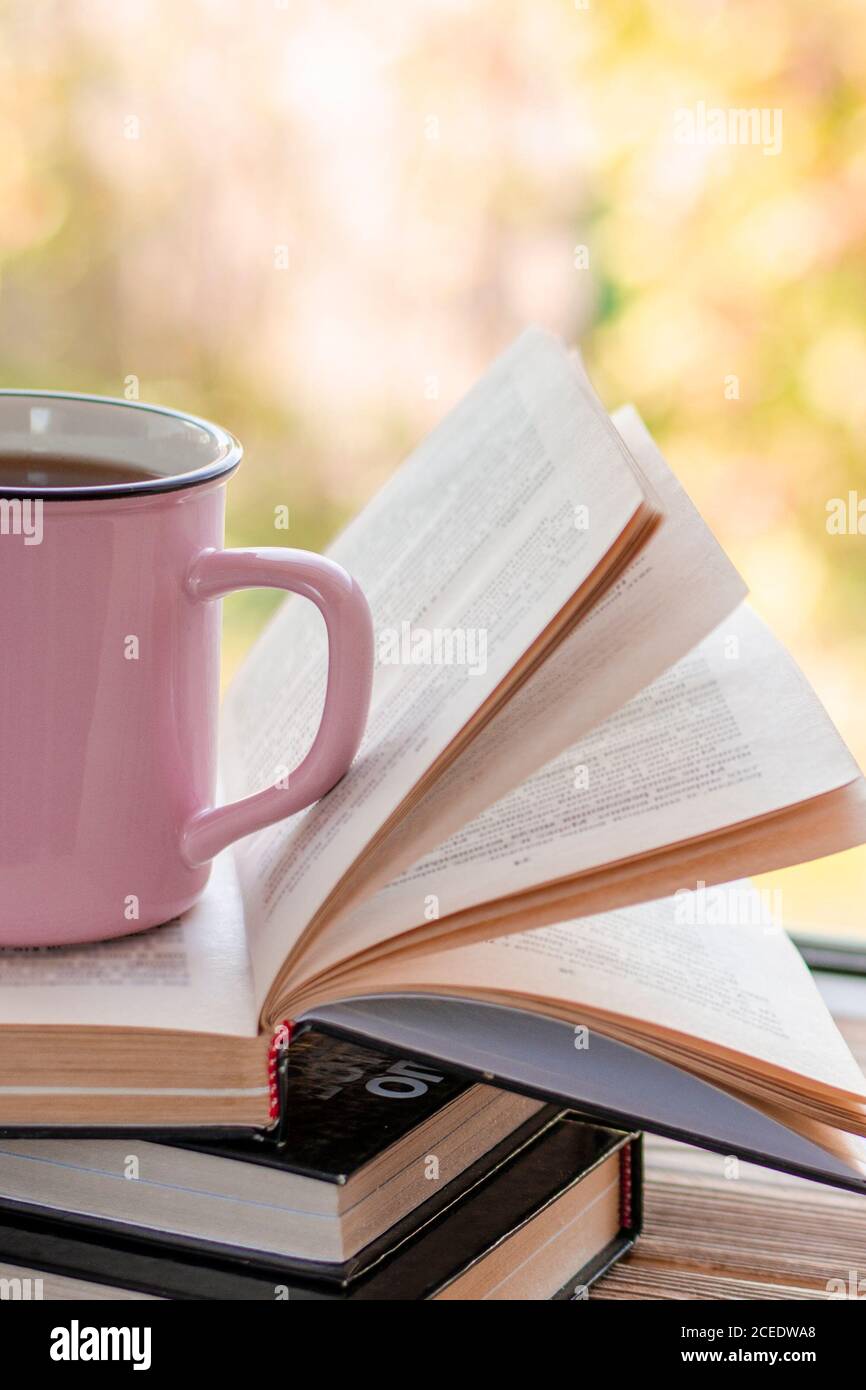 Eine rosa Tasse Tee steht auf einem Stapel von Öffnen Sie Bücher Stockfoto