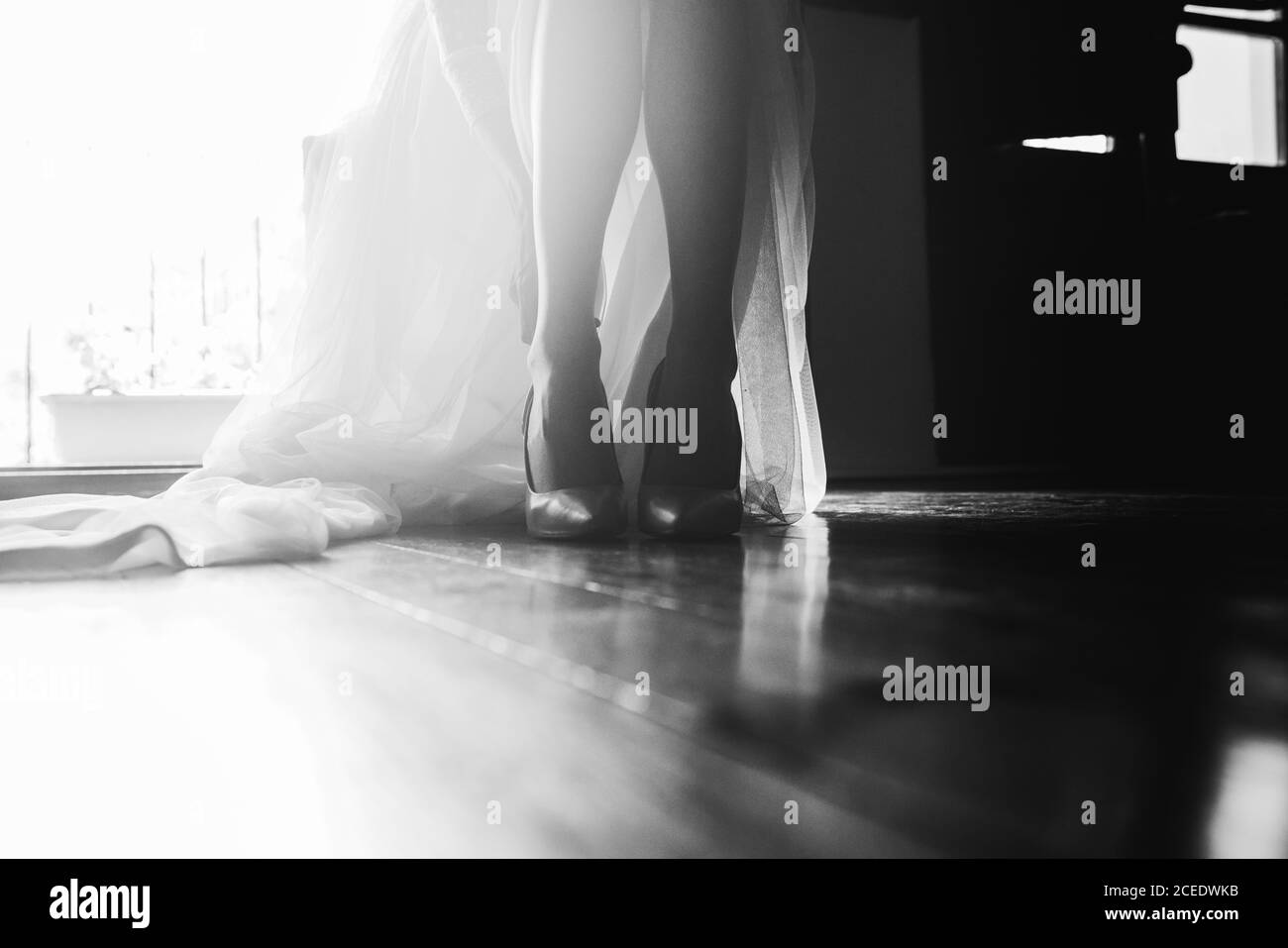 Crop-Ansicht der Braut Beine in Schuhen und bodenlange Weißes Hochzeitskleid in schwarz und weiß Farben Stockfoto