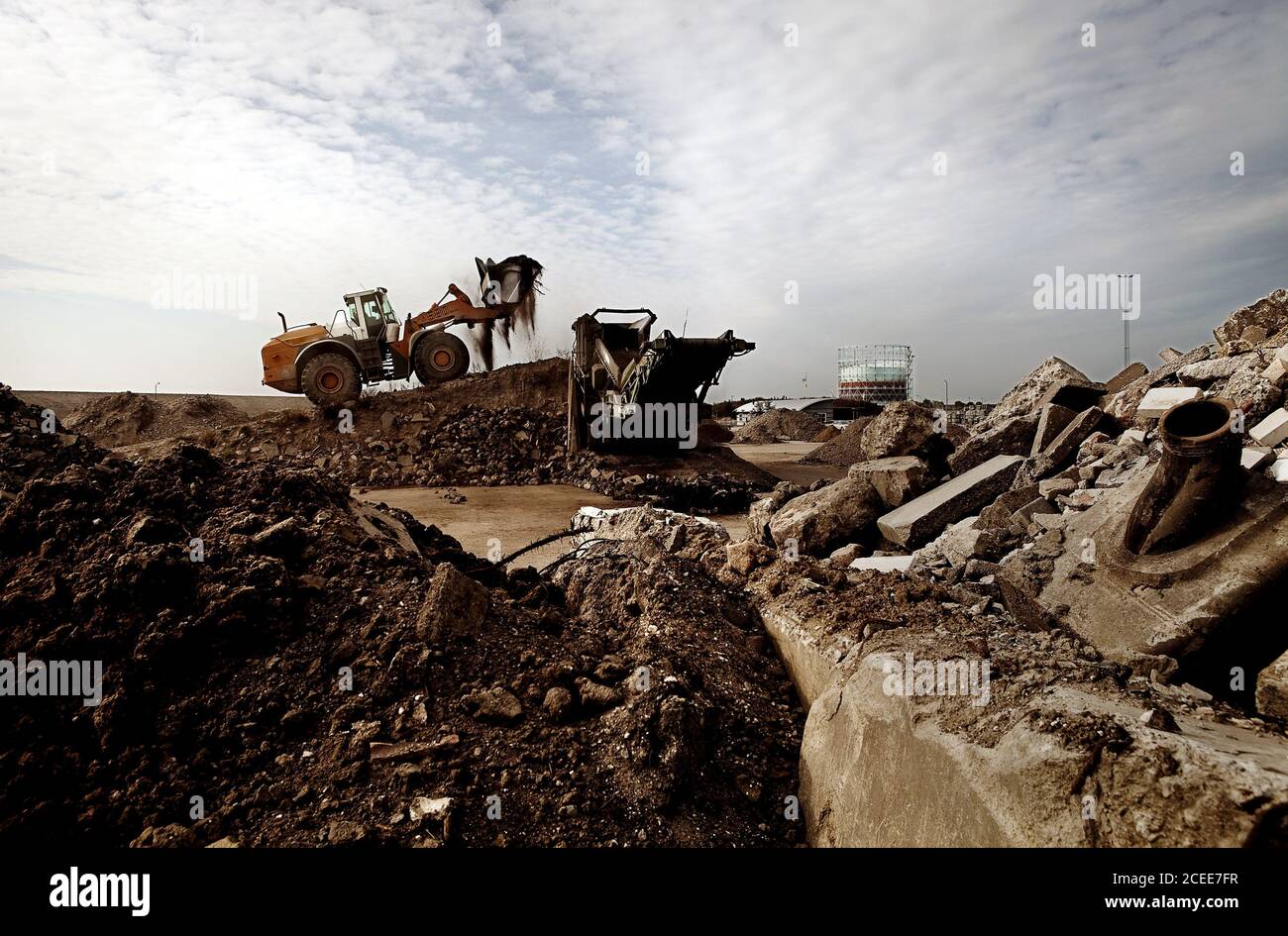 Eine Baustelle in Dänemark. Schmutz und Schlamm und eine Maschine, die vor Ort arbeitet. Wolkiger Himmel. Stockfoto