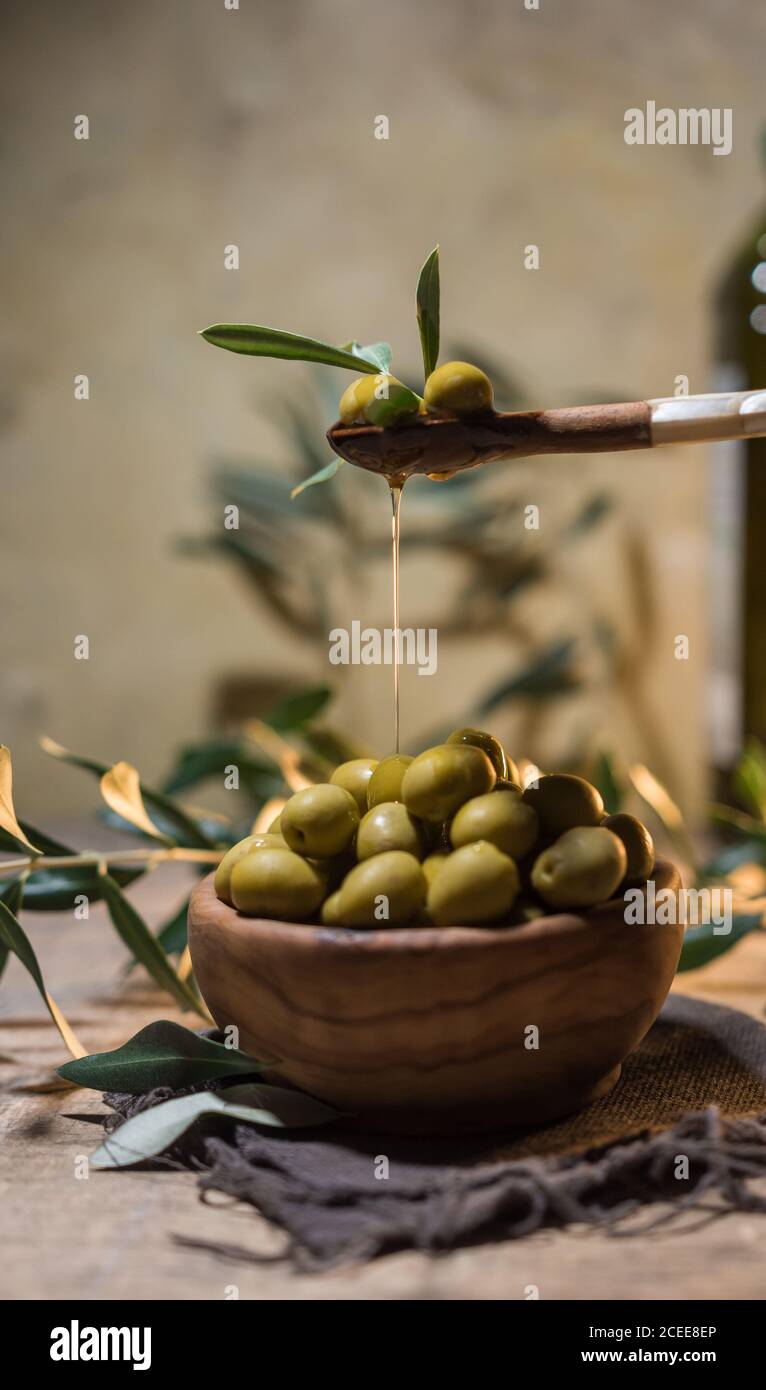Natives Olivenöl fällt auf eine Schüssel voll von Grün Oliven Stockfoto