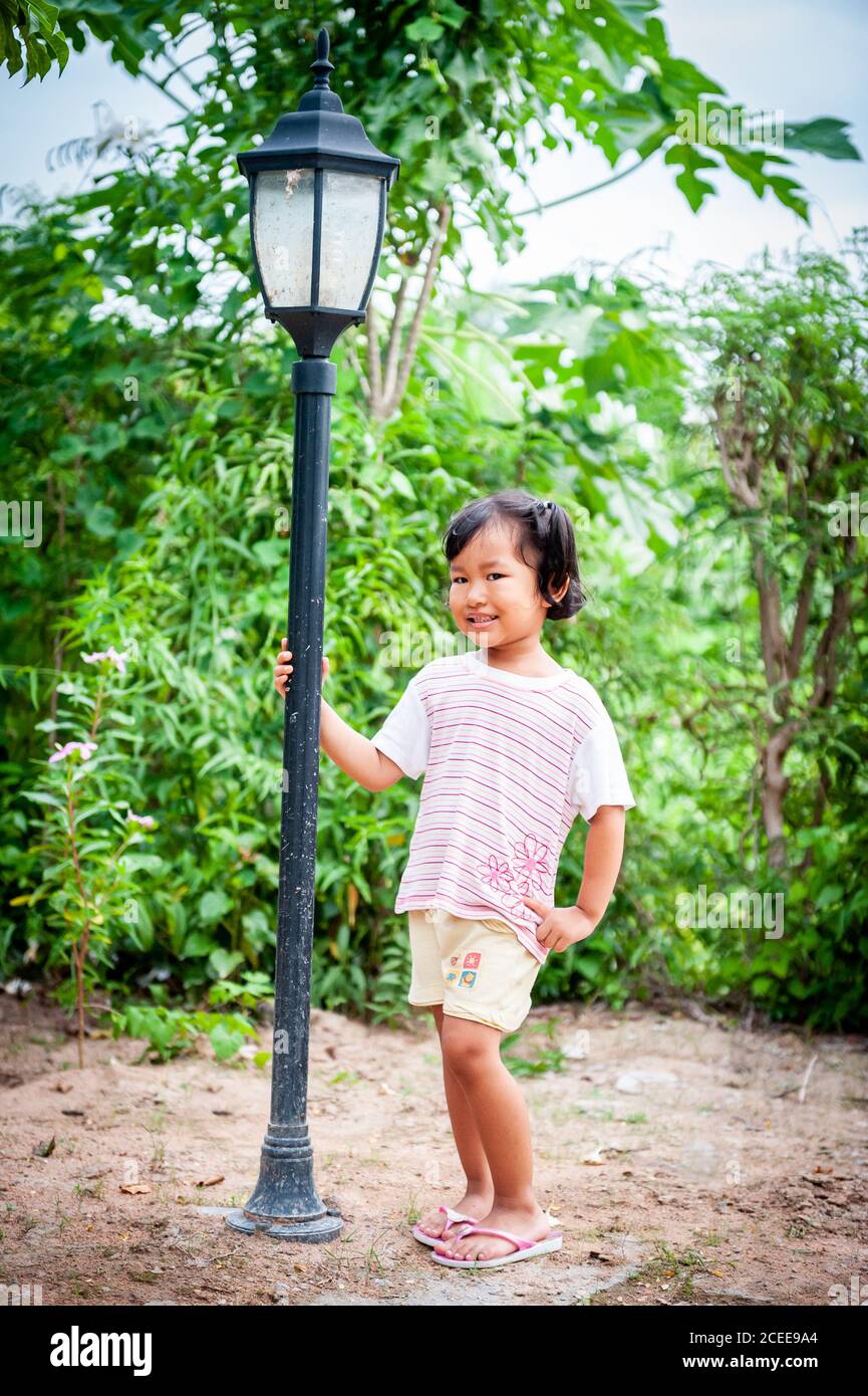 Ein junges, verspieltes Thai-Mädchen spielt im Garten ihres Familienhauses. Stockfoto