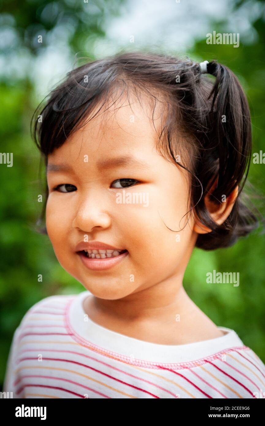 Ein junges, verspieltes Thai-Mädchen spielt im Garten ihres Familienhauses. Stockfoto
