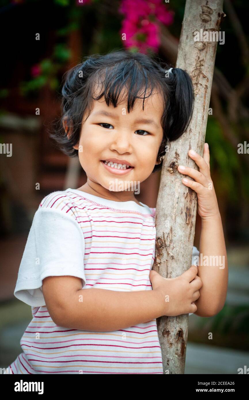 Ein junges, verspieltes Thai-Mädchen spielt im Garten ihres Familienhauses. Stockfoto