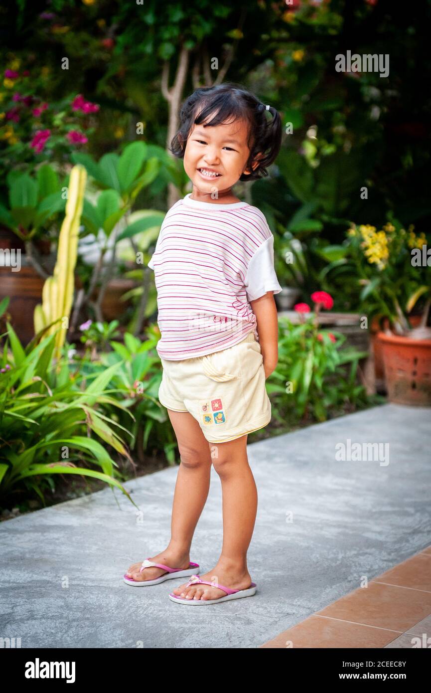 Ein junges, verspieltes Thai-Mädchen spielt im Garten ihres Familienhauses. Stockfoto