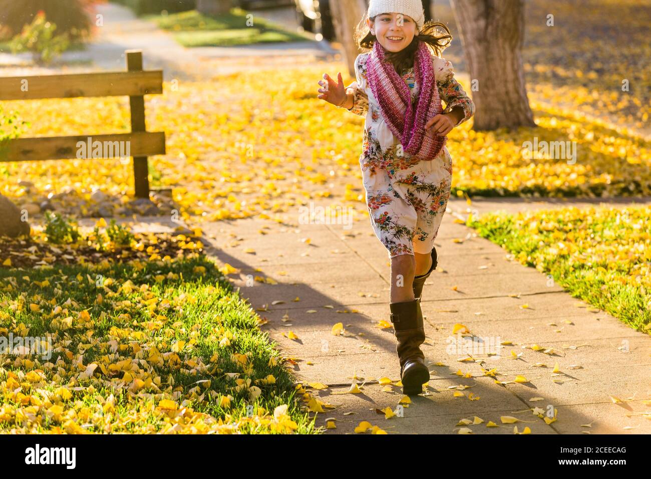 Mädchen läuft auf Gehweg zwischen gelben Blättern Stockfoto