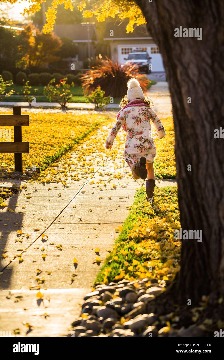 Mädchen läuft auf Gehweg zwischen gelben Blättern Stockfoto