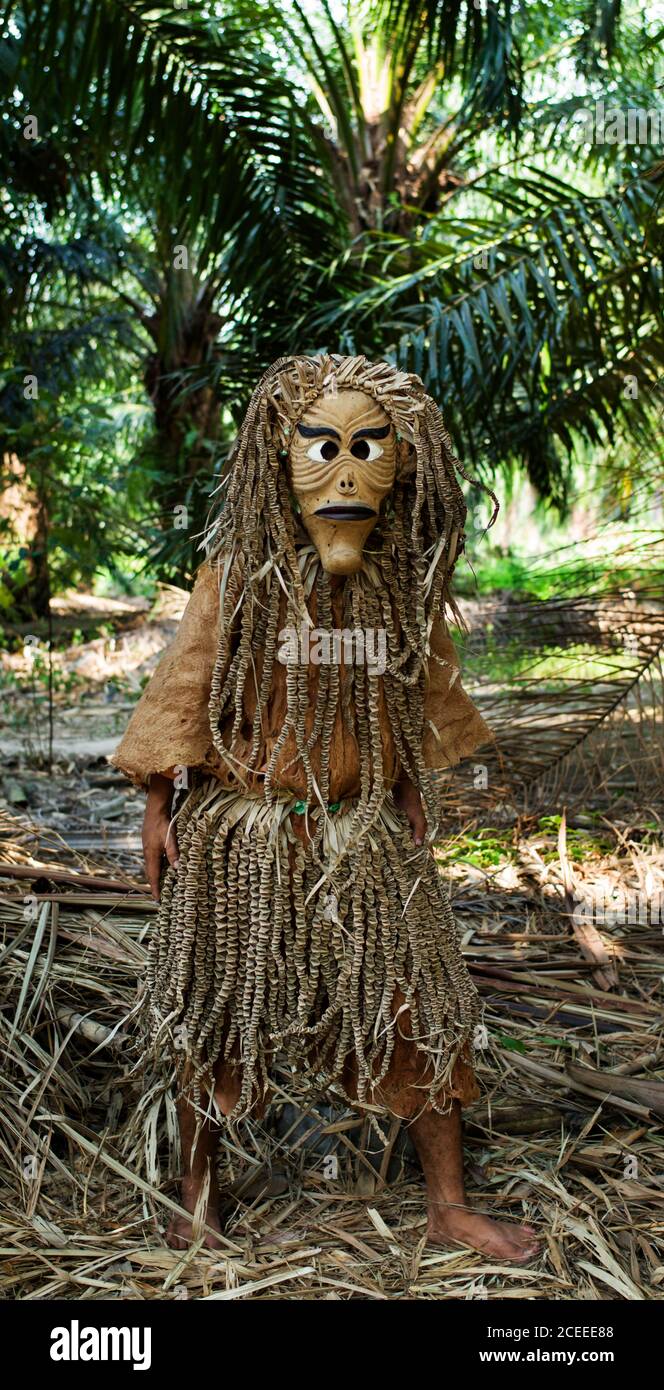 Unbekannte Person trägt authentische Kostüm mit Maske auf dem Hintergrund von Palmen im tropischen Wald stehen. Stockfoto