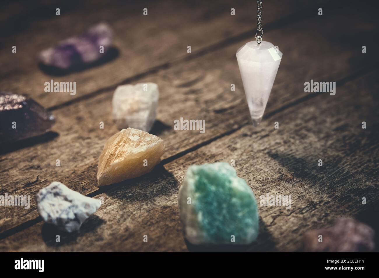 Kristall-Pendel mit heilenden Edelsteinen auf Holztisch, Spiritualität und esoterischem Hintergrund Stockfoto
