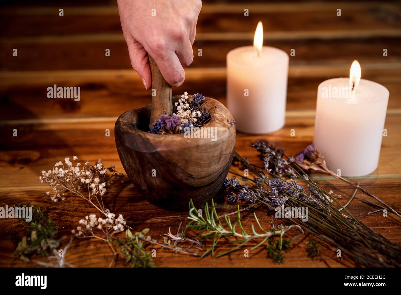 Pulverisierende Heilkräuter und Blumen mit dem Mörser, esoterische Inhaltsstoffe für eine Therapie, weibliche Hand Stockfoto