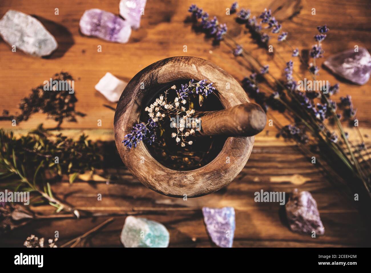 Pulverisierende Heilkräuter und Blumen mit dem Mörser, esoterische Inhaltsstoffe für eine Therapie, Flatlay Stockfoto